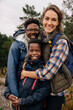 © Maskot - Portrait of father and mother embracing son while standing in forest