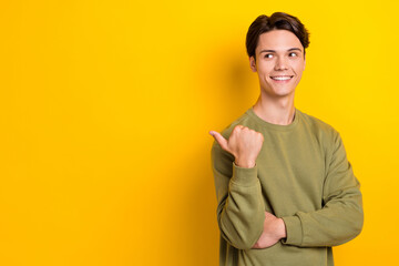 Sticker - Photo of cheerful nice person toothy smile look indicate finger empty space isolated on yellow color background