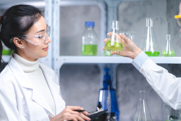 Wall Mural - young asian male and female scientist partners wearing lab coat with protective eye wear and glasses