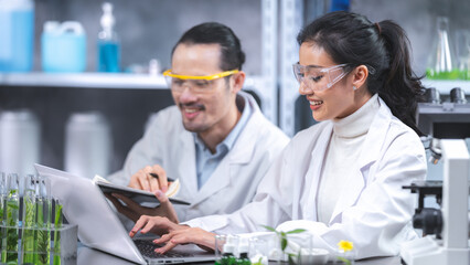Wall Mural - young asian male and female scientist partners wearing lab coat with protective eye wear and glasses