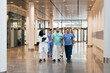 © Maskot - Multiracial group of male and female hospital staff discussing while walking in lobby