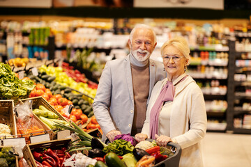 Wall Mural - A happy healthy senior couple is buying fresh vegetables at the supermarket.