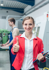 Wall Mural - Manager giving thumbs-up sign standing on the factory floor in industrial hall