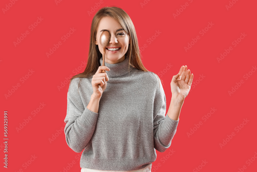 Beautiful woman with golden spoon on red background