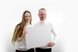 © Oleksandra - adult man and a young woman holding a picture in their hands frame for advertising text smiling sincere laughter white clothes white background place empty frame paper cardboard poster banner