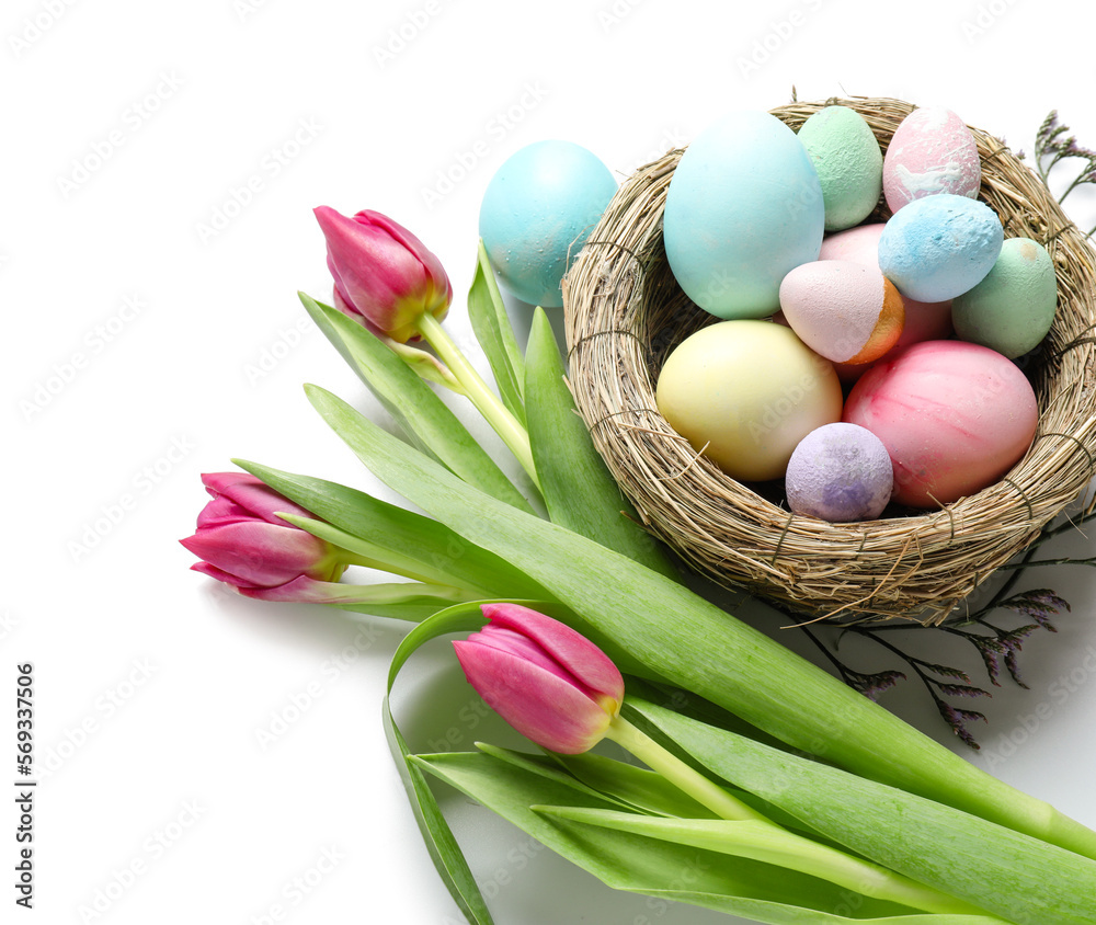 Composition with nest of Easter eggs and beautiful tulip flowers on white background