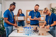 © Zamrznuti tonovi - Diverse volunteers working in a charity donation center and packing clothes and food