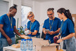 © Zamrznuti tonovi - Diverse volunteers working in a charity donation center and packing clothes and food