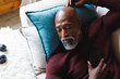 © Wavebreak Media - High angle view of bald african american senior man with mobile phone sleeping on couch at log cabin