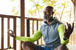 © Wavebreak Media - Bald african american senior man with eyes closed meditating in balcony at log cabin