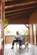 © Wavebreak Media - African american senior man playing guitar while sitting on chair with coffee on table in log cabin