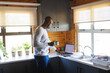 © Wavebreak Media - Side view of african american bald senior man holding coffee mug and using laptop on kitchen counter