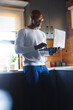 © Wavebreak Media - Serious african american bald senior man wearing eyeglasses using laptop while standing in kitchen