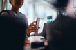 © Drazen - Close up of athletic woman checking in with cell phone at reception desk in gym.