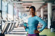 © Drazen - Portrait of happy African American sportswoman with water bottle in gym looking at camera.