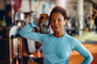 © Drazen - Black female athlete with kettlebell in gym looking at camera.