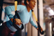 © Drazen - Close up of black athletic woman working out with suspension straps in gym.