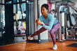 © Drazen - African American athletic woman practicing side lunge with suspension strap while working out in gym.