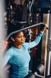 © Drazen - African American athletic woman using exercise machine during strength training in gym.