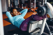 © Drazen - Black athletic woman practicing sit ups while working out in gym.
