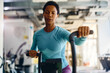 © Drazen - determined African American sportswoman cycling on exercise bike in gym.