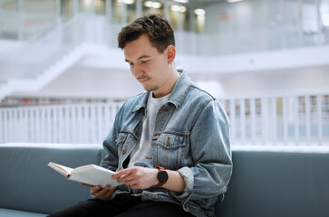 Wall Mural - Education, library and man with a book, reading and studying for a test, exam and knowledge. Male, student and academic with journal, research or focus on learning, peace and relax with calm or quiet