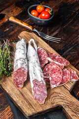 Wall Mural - Spanish dry salami sausage Fuet on wooden cutting board. Black background. Top view