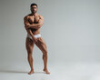 © Serge Lee - Sexy muscular man in white underwear posing in studio. Handsome bodybuilder standing on grey background. Big male model showing his muscles.