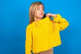 Fototapeta  - caucasian teen girl wearing yellow sweater over blue studio background stressed, anxious, tired and frustrated, pulling shirt neck, looking frustrated with problem