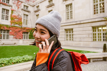 Joyful asian woman talking on mobile phone during walk in old city