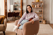 Beautiful asian woman smiling at camera while sitting at home