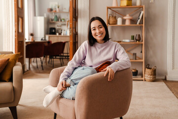 Wall Mural - Beautiful asian woman smiling at camera while sitting at home