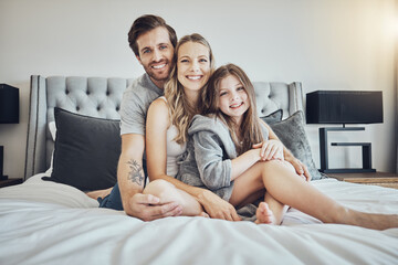 Wall Mural - Love, relax and portrait of a family on a bed embracing, bonding and resting together at their home. Happiness, mother and father sitting and relaxing with their girl child in their bedroom in house.