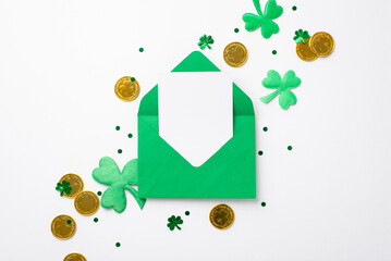 St Patrick's Day concept. Top view photo of open green envelope with letter gold coins shamrocks and confetti on isolated white background with copyspace