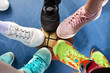 © Georgii - Bright and colorful sport shoes circle with basket ball top view. Set of different sneakers on blue floor, copy space. Team game, competition concept