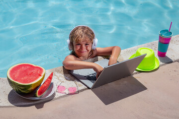 Wall Mural - Child with laptop in swimming pool in summer day. Work outside concept, Business and summer.