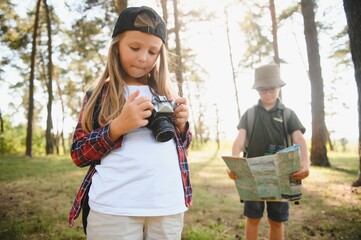 Wall Mural - Group of curious happy school kids in casual clothes with backpacks exploring nature and forest together on sunny autumn day.