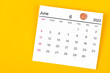 A June 2023 calendar and wooden push pin on yellow background.