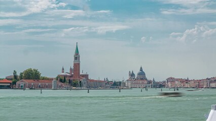 Wall Mural - Panoramic sea view of the San Giorgio Maggiore island and basilica Santa Maria della Salute timelapse in Venice, Italy. Cloudy summer day. Boats floating on the water