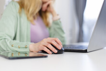 Adult Woman Working On A Computer At Home. Unrecognizable White Female Person Clicking With Wireless Mouse On A Laptop