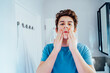 © okrasiuk - Concentrated caucasian teenage boy with acne problem take care his face skin at home. He looking in the mirror and cleaning face with washing lotion in bathroom. Teenager skin care process