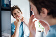 © okrasiuk - Concentrated caucasian teenage boy with acne problem at his face looking in mirror at home bathroom. Teenager skin care every day treatment process. Selective focus.