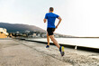 male runner athlete running on sea embankment