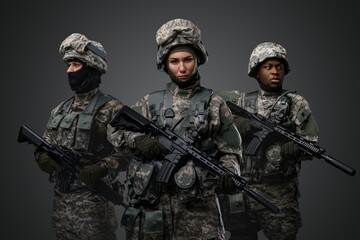 Wall Mural - Brave female soldiers with two comrades looking at camera isolated on grey.