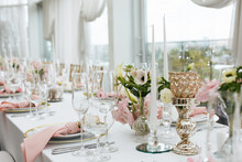 Wedding Decorations. Served Wedding Table With Decorative Fresh Pink Flowers And Candles. Celebration Details. Flower Composition Roses Plates And Candles In Candlesticks