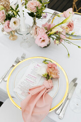 table service. close up a plate decorated with pink flowers, a folded napkin and a restaurant menu. 