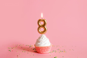 Greeting card March 8. Cupcake with white cream and candle number 8 isolated on pink background