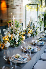 Wall Mural - Table setting decorated with a gray tablecloth, silver plates, blue napkins and compositions of white, blue flowers and candles. Concept of wedding decorations 