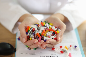 Wall Mural - Female pharmacist shows bunch of different colorful pills while sitting at table.