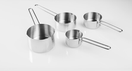  Kitchen utensils.Group of small stainless steel ladles on a glassy white background